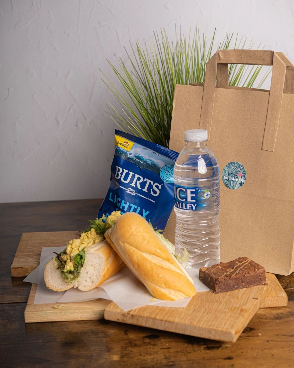 An individual lunch bag with a filled baguette, crisps and a brownie